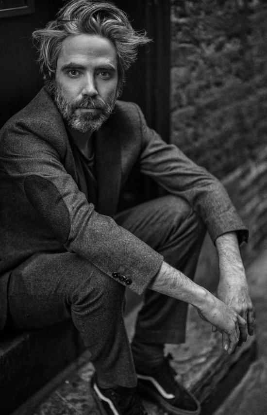 Photo de Patrick Watson assis en noir et blanc 