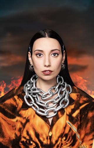 Photo portrait de l'artiste Kalika avec un tenue orange et des chaînes autour du cou