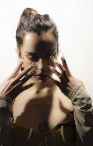 Photo portrait de l'artiste Oklou avec les mains devant le visage